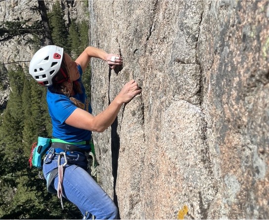 Climber performing gaston climbing move with left arm on rock climb.